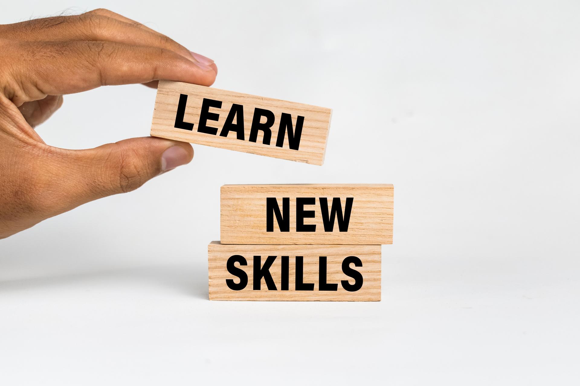 male hand put wooden blocks with learn new skills words text isolated on white background