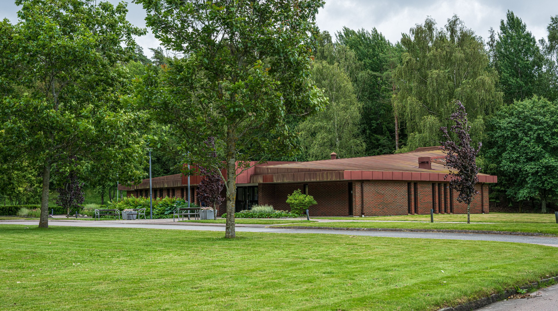 Red roofed brick building in green cemetery..