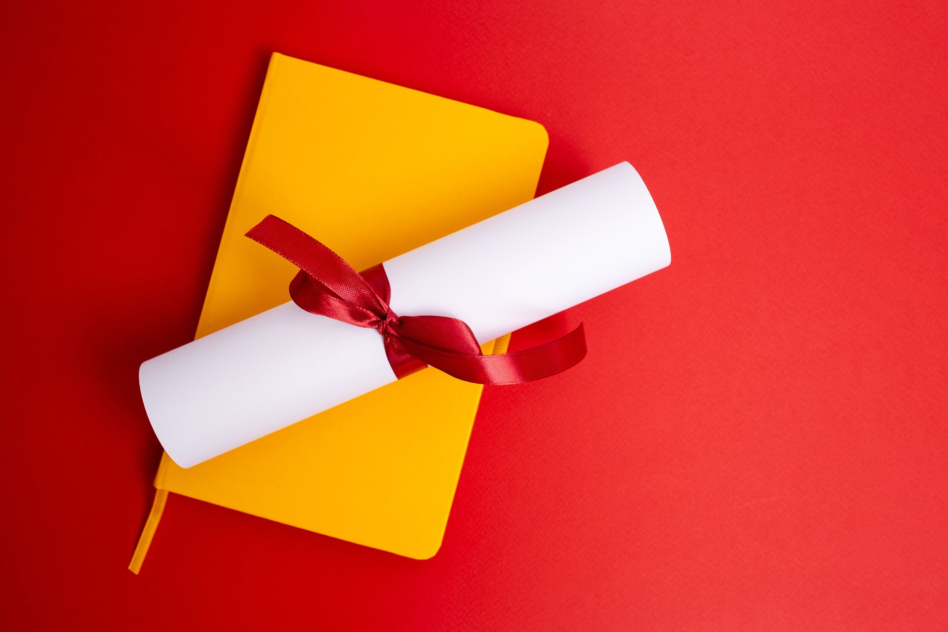Diploma tied with a red ribbon on a colored background. Education and science concept
